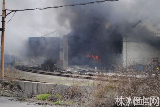 在距事故現(xiàn)場(chǎng)300米左右，拉起了警戒線。因技術(shù)、場(chǎng)地原因，救援難度較大。站在警戒線外仍可看見(jiàn)倉(cāng)庫(kù)內(nèi)的明火。（若葉 攝）