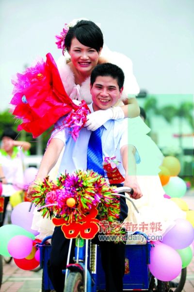 三輪車當婚車，新郎載著新娘圍繞大運主場館騎行一周。昨日，一對新人在龍崗區龍翔大道上演浪漫環保、大運主題婚禮。