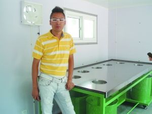 民間環(huán)保人士驢屎蛋站在自己投資建設(shè)的“綠房子”室內(nèi)。