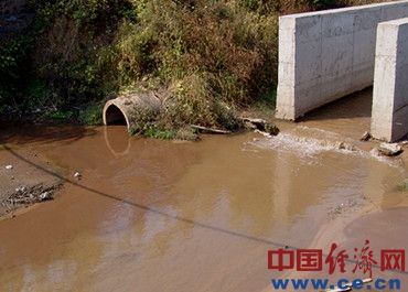 圖為九鋼老廠區東面的排污口，方形污水渠中流出的是PH值達12的強堿性渾濁污水，圓水泥管中排出泥漿狀污水，上面還泛著油花，兩種污水在排口附近涇渭分明。